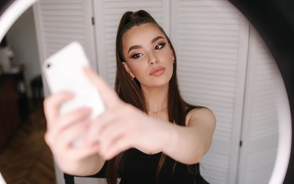 Eine junge, gestylte Frau macht ein Selfie.