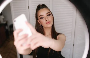 Eine junge, gestylte Frau macht ein Selfie.