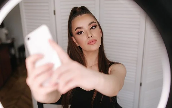 Eine junge, gestylte Frau macht ein Selfie.