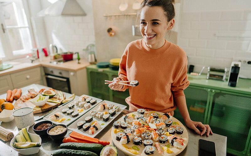 Eine Frau steht in der Küche mit zubereitetem Sushi.