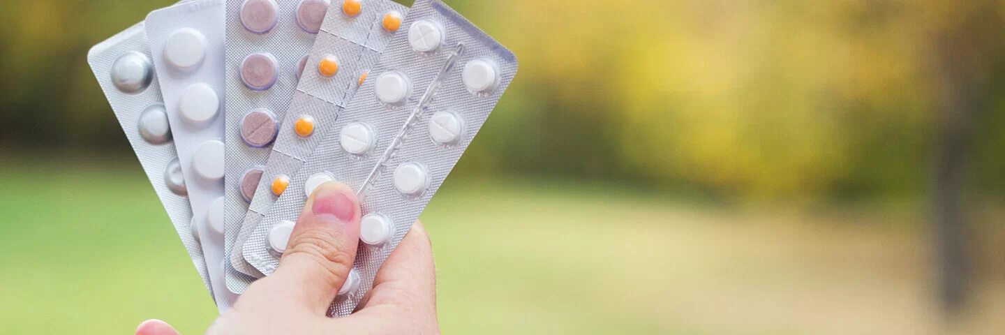 Eine Hand hält fünf unterschiedliche Blisterpackungen mit Medikamenten hoch.