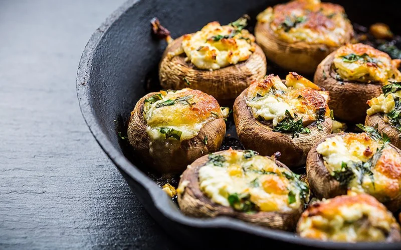 Gefüllte Champignons mit Käse und Kräutern in einer gusseisernen Pfanne.