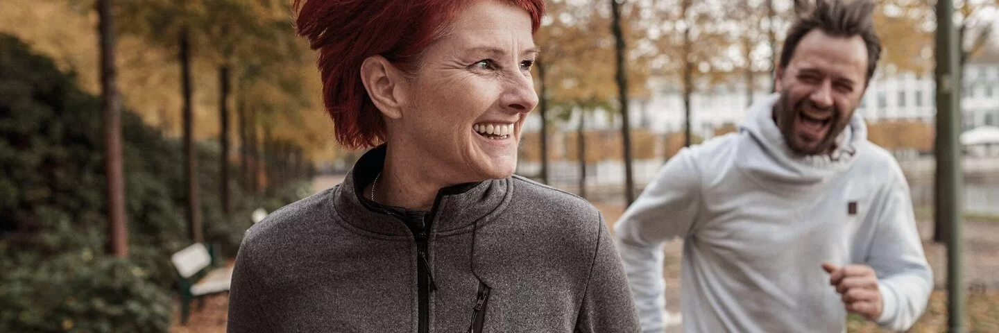 Auf dem Bild ist links eine Frau und rechts ein Mann zu sehen, die beide joggen.