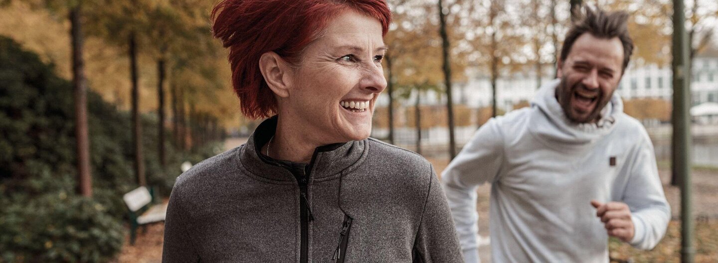 Auf dem Bild ist links eine Frau und rechts ein Mann zu sehen, die beide joggen.