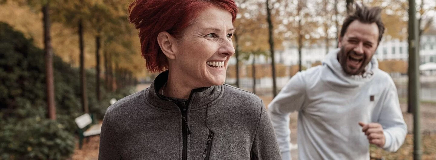 Auf dem Bild ist links eine Frau und rechts ein Mann zu sehen, die beide joggen.