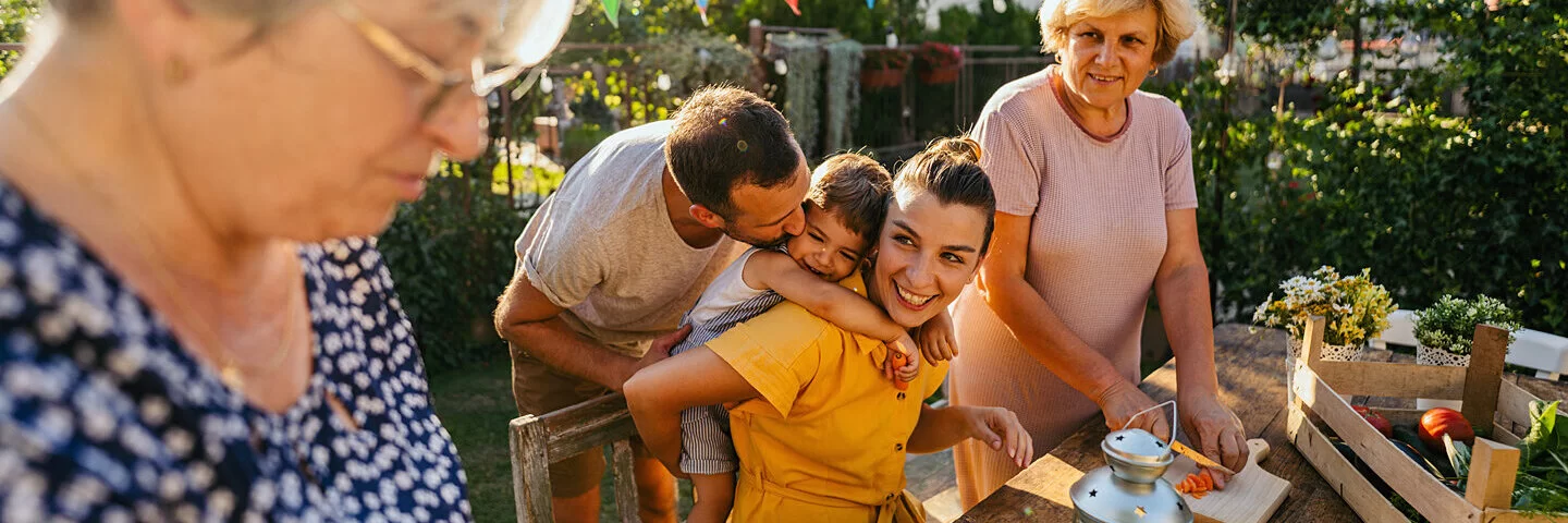 Mehrere Generationen einer deutschen Familie bereiten ein gesundes Essen im Garten zu.