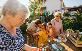Mehrere Generationen einer deutschen Familie bereiten ein gesundes Essen im Garten zu.