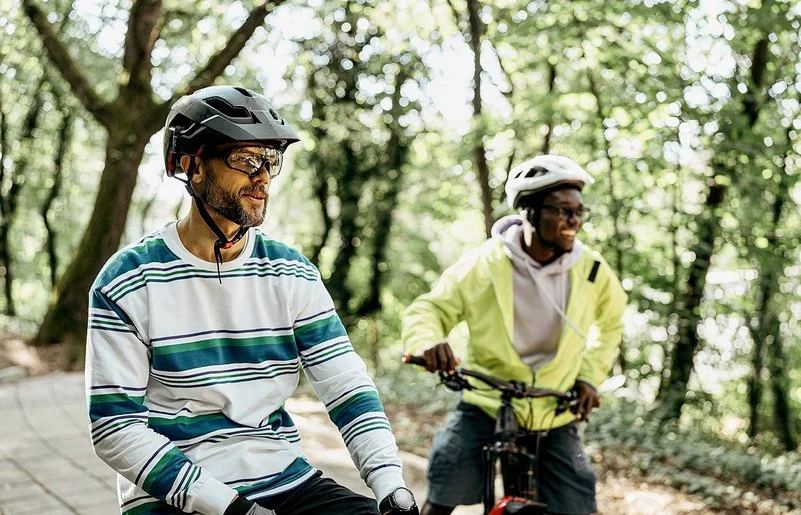 Zwei Männer mit Fahrradhelmen stehen mit ihren Fahrrädern auf einem Waldweg.