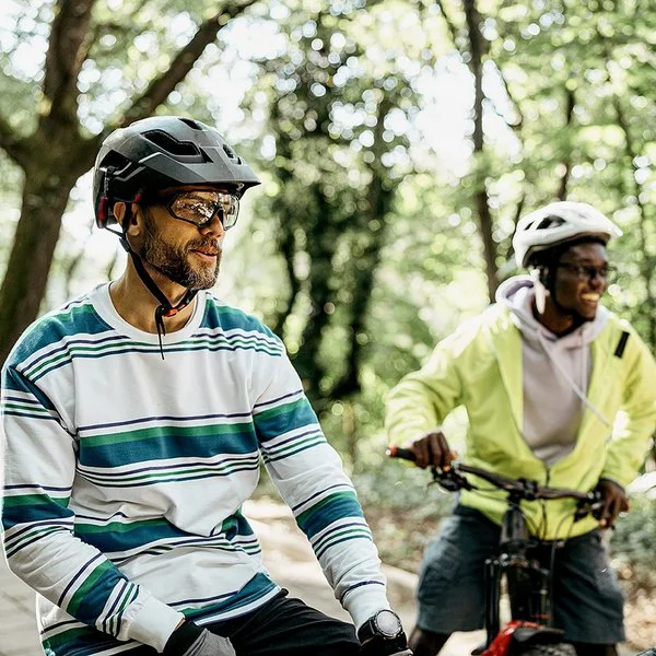 Zwei Männer mit Fahrradhelmen stehen mit ihren Fahrrädern auf einem Waldweg.