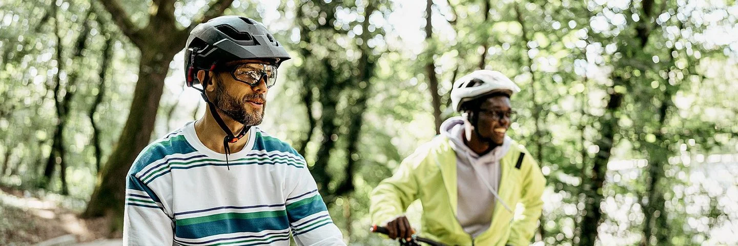 Zwei Männer mit Fahrradhelmen stehen mit ihren Fahrrädern auf einem Waldweg.