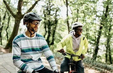 Zwei Männer mit Fahrradhelmen stehen mit ihren Fahrrädern auf einem Waldweg.