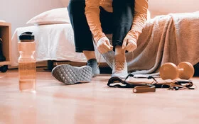 Eine Frau zieht Sportschuhe für Indoor-Walking zu Hause an.