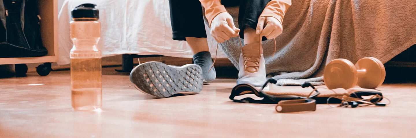 Eine Frau zieht Sportschuhe für Indoor-Walking zu Hause an.