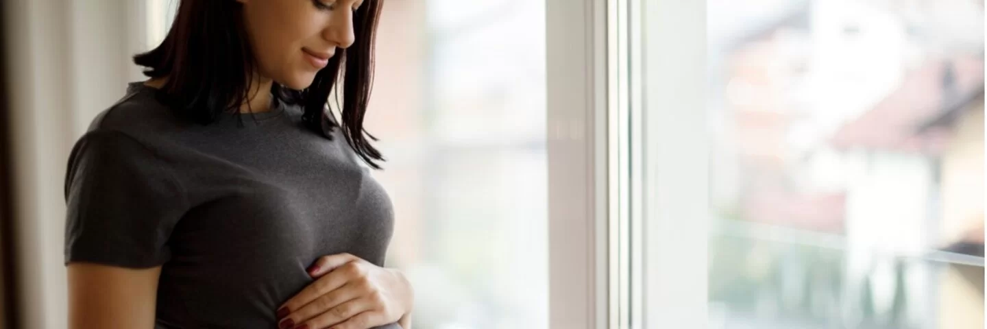 Schwangere Frau hält sich in freudiger Erwartung den Babybauch
