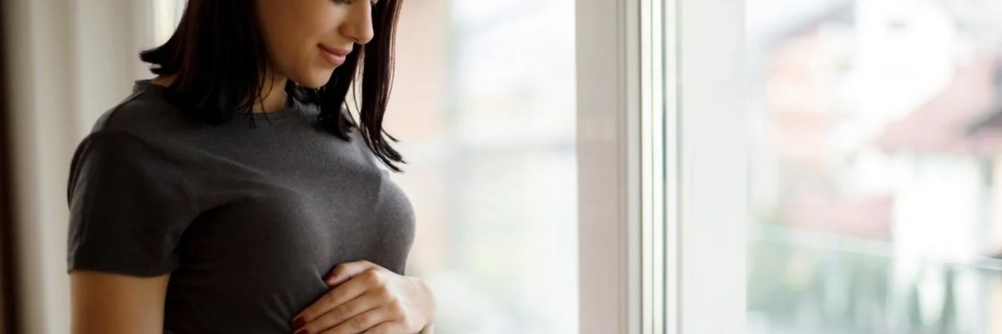 Schwangere Frau hält sich in freudiger Erwartung den Babybauch