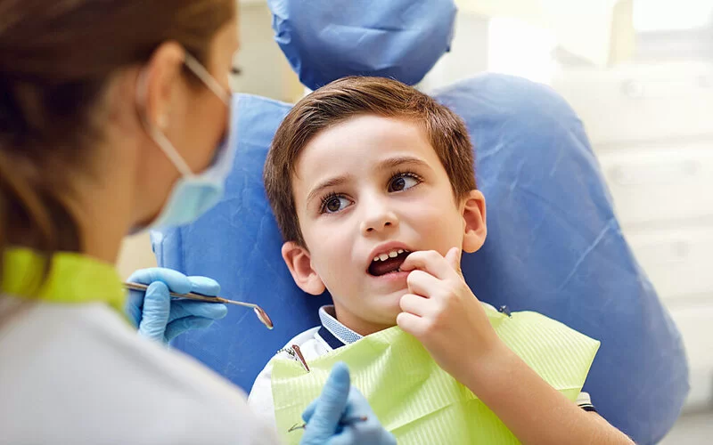 Ein kleiner Junge lässt seine Milchzähne von einer Zahnärztin kontrollieren.
