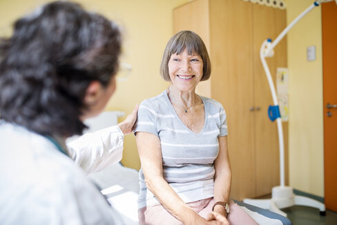 Eine Ärztin berät eine ältere Frau im Krankenhaus. Diese Beratung ist wichtig, da die Behandlung bei Brustkrebs individuell verschieden ist.