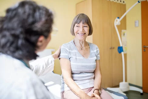 Eine Ärztin berät eine ältere Frau im Krankenhaus. Diese Beratung ist wichtig, da die Behandlung bei Brustkrebs individuell verschieden ist.