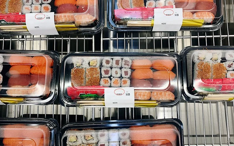 Mehrere Plastikschalen liegen vor- und nebeneinander, in denen Sushi verpackt ist.