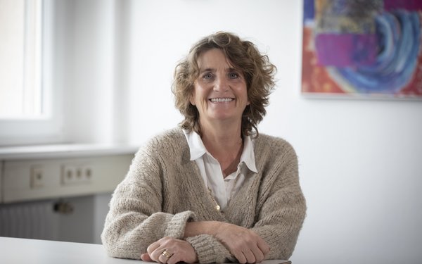 Antje Noah-Scheinert sitzt am Tisch und lächelt in die Kamera.