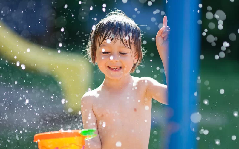 Ein kleiner Junge spielt und lacht in einem Wasserpark.
