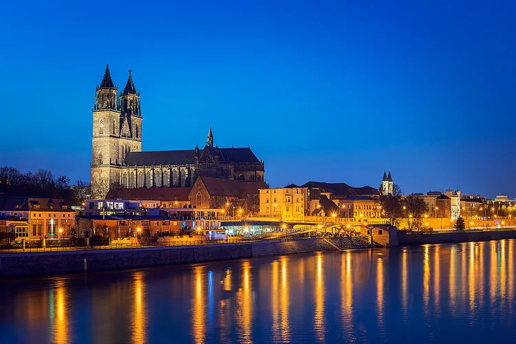 Blick über die Elbe auf das beleuchtete Magdeburg bei Nacht.