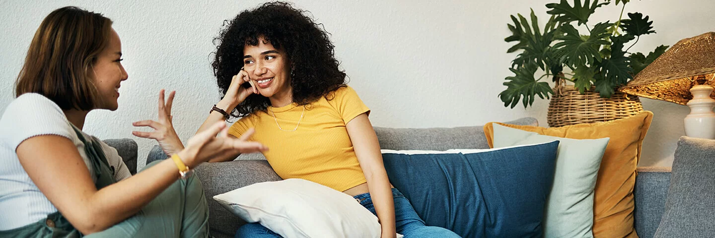 Ein Gespräch über Begriffe wie Schamlippen: Zwei junge Frauen sitzen auf dem Sofa und unterhalten sich.