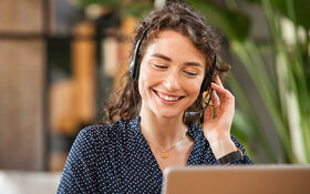 Eine empathische Mitarbeiterin bei einem Sorgentelefon spricht mit einer Person über ein Headset.