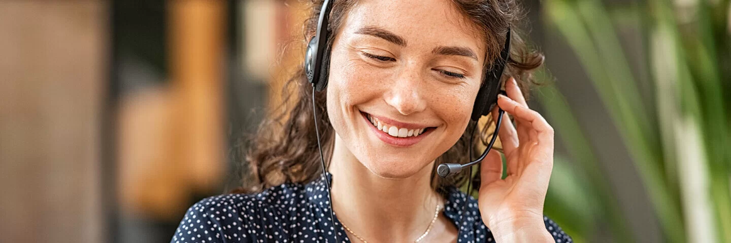 Eine empathische Mitarbeiterin bei einem Sorgentelefon spricht mit einer Person über ein Headset.