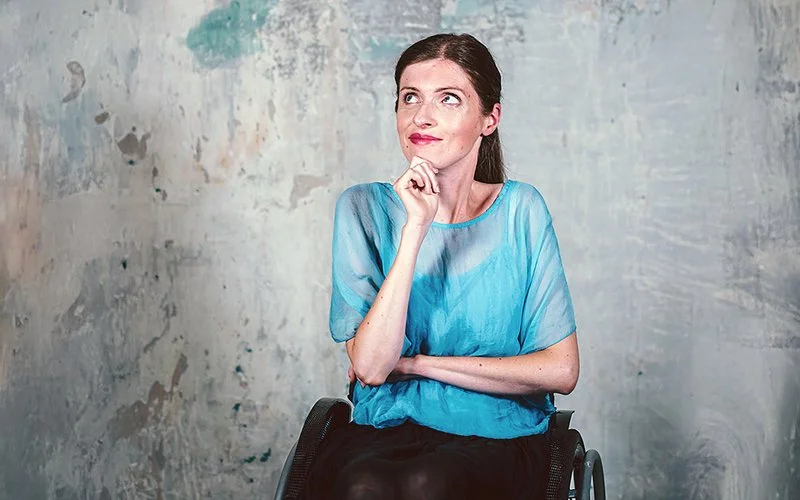 Adina Hermann sitzt in einer blauen Bluse im Rollstuhl.