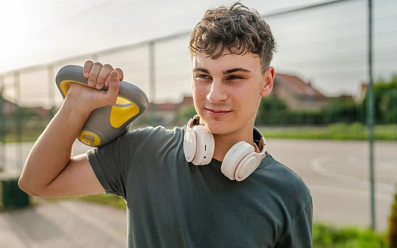 Ein Jugendlicher trainiert im Freien mit einem Kettlebell.