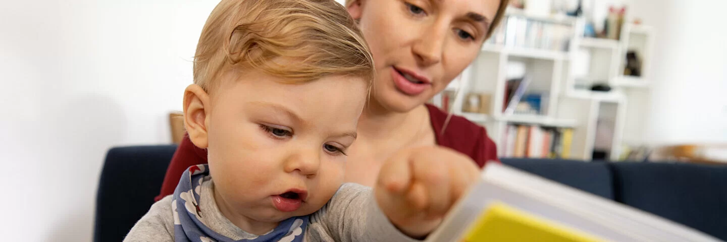 Mutter unterstützt die Sprachentwicklung ihres Kindes, indem sie ihm etwas vorliest.