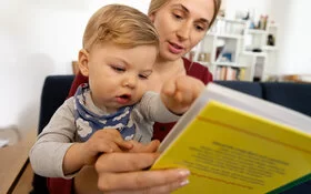 Mutter unterstützt die Sprachentwicklung ihres Kindes, indem sie ihm etwas vorliest.