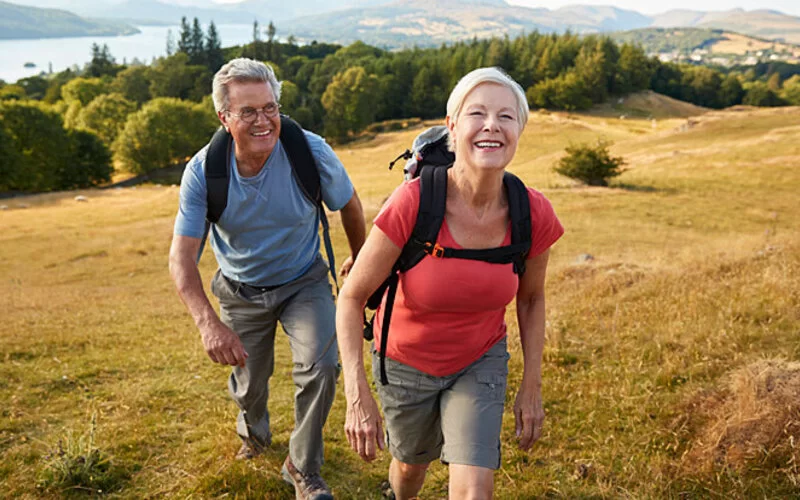 Um einer tiefen Beinvenenthrombose vorzubeugen, gehen zwei ältere Menschen wandern.
