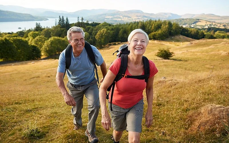 Um einer tiefen Beinvenenthrombose vorzubeugen, gehen zwei ältere Menschen wandern.
