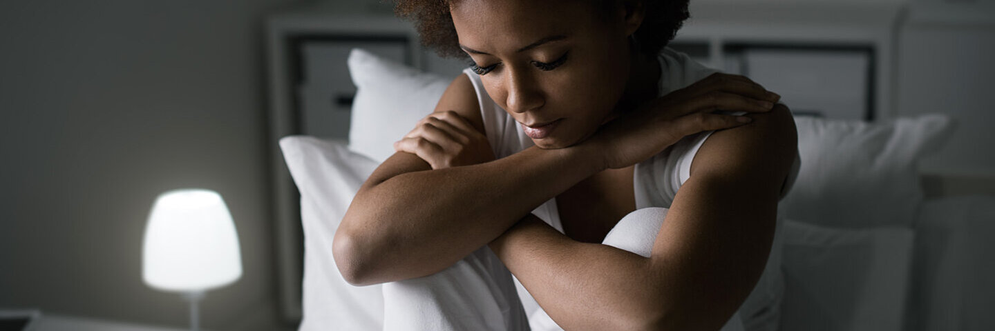Was kann man gegen Depressionen tun?“, überlegt eine depressive Frau auf dem Bett.