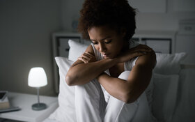Was kann man gegen Depressionen tun?“, überlegt eine depressive Frau auf dem Bett.