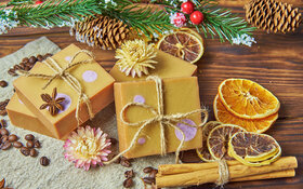 Handgemachte Seifenstücke mit weihnachtlicher Dekoration liegen auf einem Holztisch.