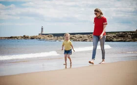 Eine Mutter und Kind sind am Strand an der Nordsee und spazieren.