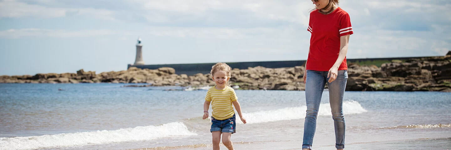 Eine Mutter und Kind sind am Strand an der Nordsee und spazieren.