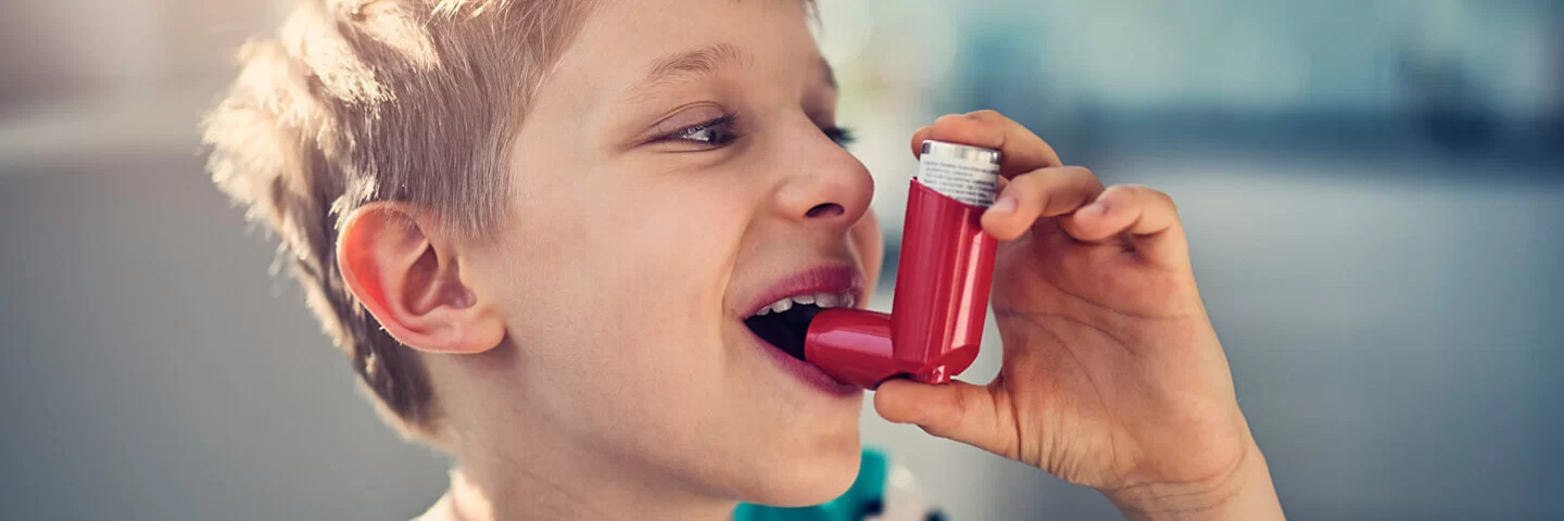 Kleiner Junge benutzt Asthmaspray.