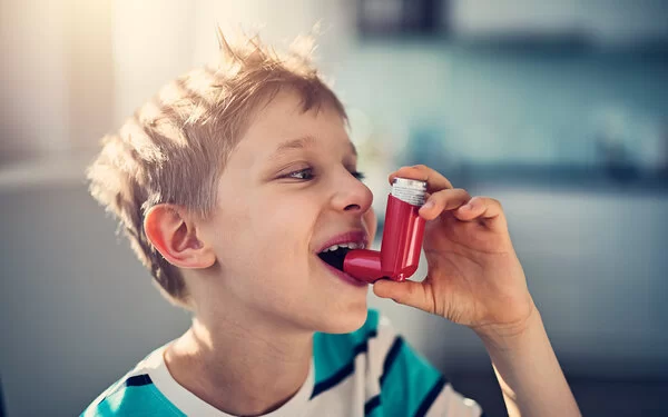 Kleiner Junge benutzt Asthmaspray.