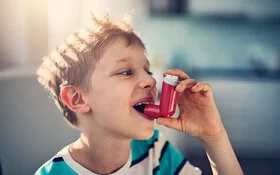 Kleiner Junge benutzt Asthmaspray.