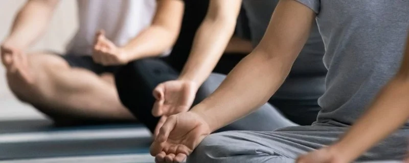 Eine Gruppe meditiert gemeinsam auf ihren Yoga-Matten.