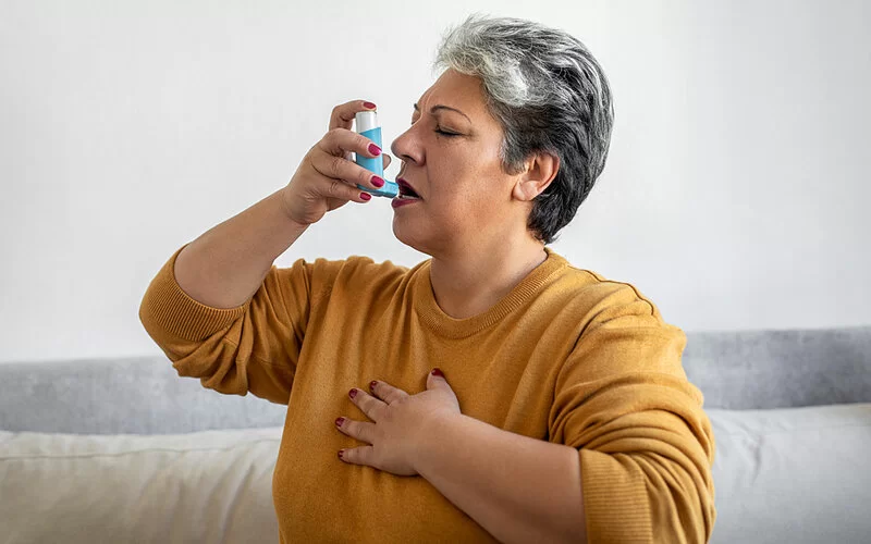 Eine ältere Frau benutzt einen Inhalator gegen ihre Atemnot.