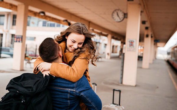 Junges verliebtes Paar führt eine Fernbeziehung und schließt sich zur Begrüßung am Bahnsteig in die Arme.