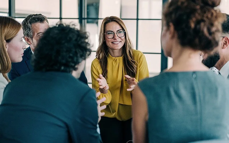 Eine Frau steht lächelnd in einer Gruppe von Menschen.