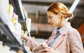 Frau mit Zöliakie schaut im Supermarkt nach glutenfreien Produkten.