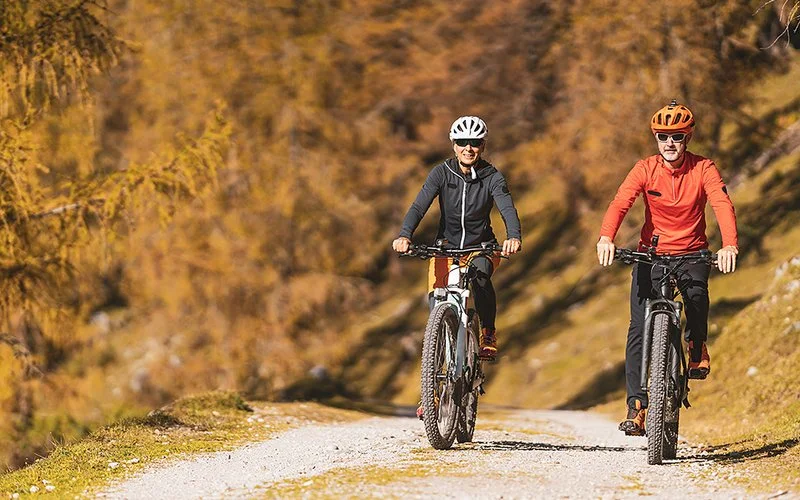 Ein Paar in mittlerem Alter fährt gemeinsam Mountainbike im Wald.