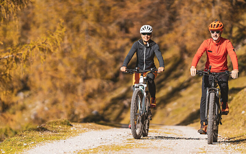Ein Paar in mittlerem Alter fährt gemeinsam Mountainbike im Wald.